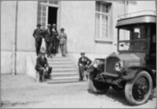 [Mężczyźni w garniturach i kapeluszach przed budynkiem głównym adminstracji fabryki Schneidera w Harfleur]